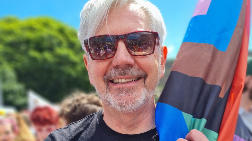 man wearing sunglasses holding pride flag